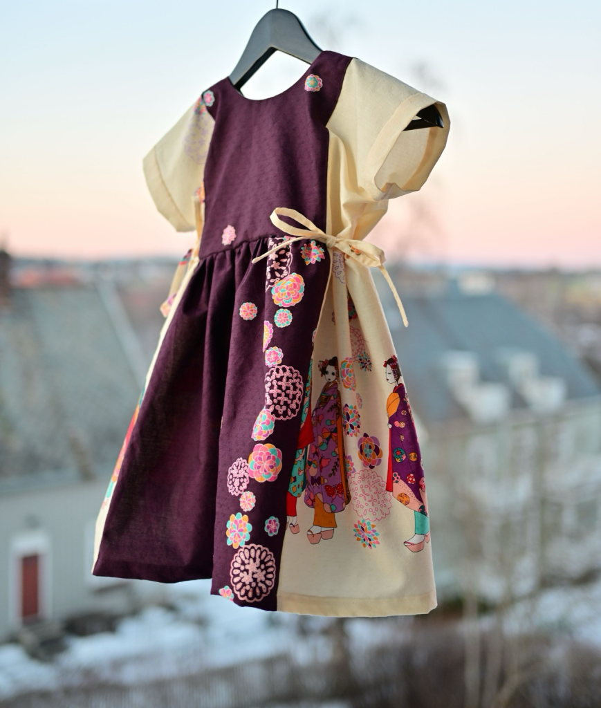 Showing front of the same dress. No figures on the center front (purple part of the skirt. Bodice is likewise simple. Both have off-center stylised flowers. 