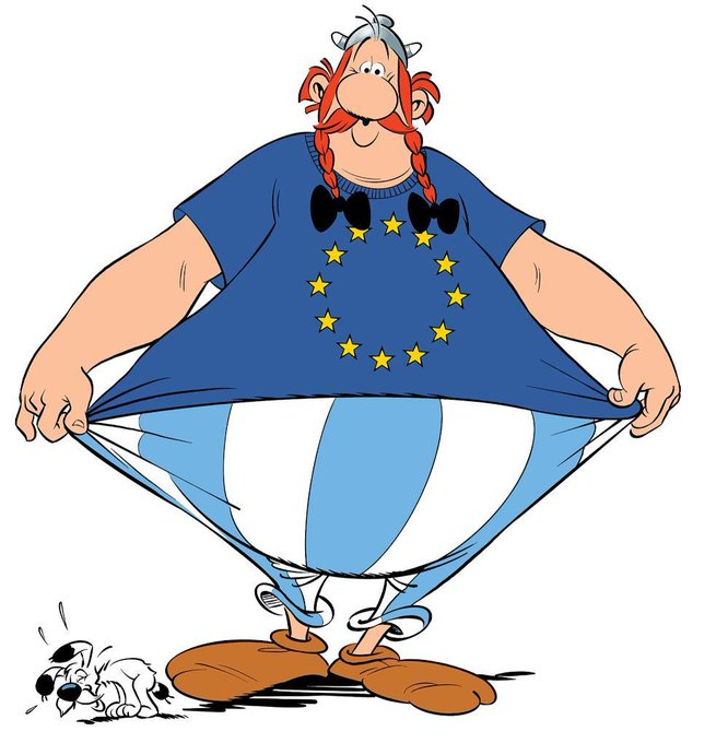 Ganzfigur vor hellem Hintergrund: Obelix trägt ein blaues T-Shirt mit gelben Sternen im Kreis und zieht es seitlich auseinander. Darunter eine blau-weiß gestreifte Hose. Unten links sitzt Idefix, ein kleiner weißer Hund mit schwarzen Ohren.