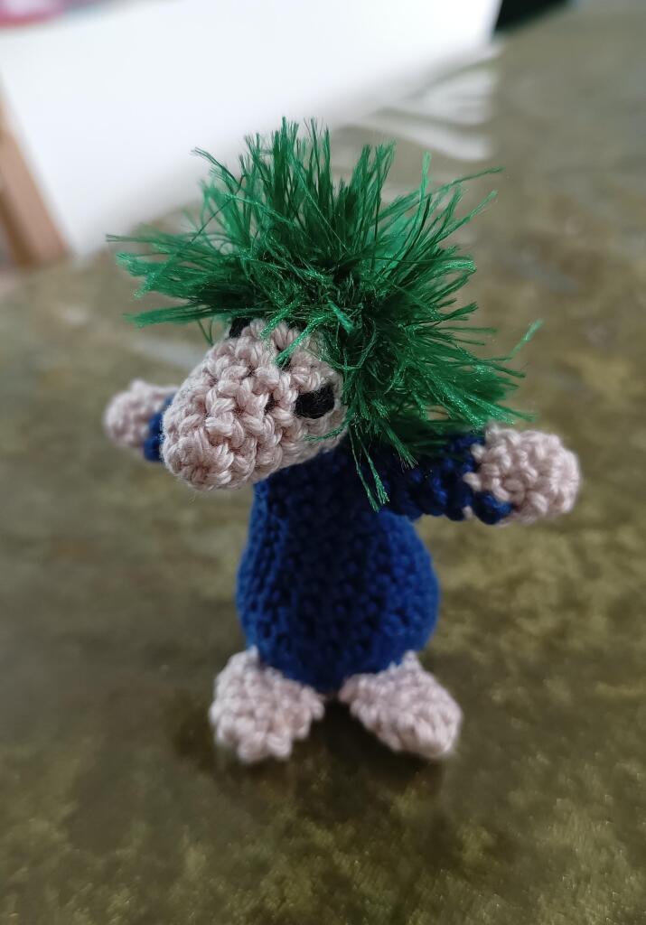 A crocheted lemming in blocker position, with its arms wide.
