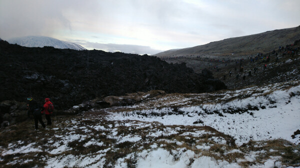 A lava field "wall" of solidified black lava, about 4 meters tall. Curled turf visible right in front of it, clearly pushed by it over time.