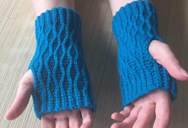 Hands wearing blue fingerless gloves with an embossed wavy pattern 