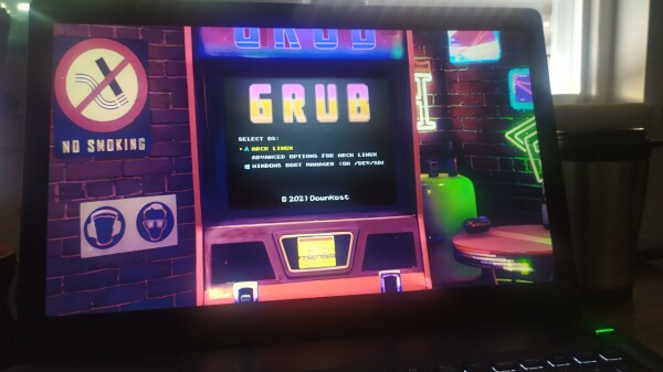 A GRUB (the pretty much de-facto Linux Bootloader) splash screen where the background is an arcade videogame machine in a shopping mall arcade and the fonts have been modified as well to match an old pacman game.

Prompts to boot are: Arch Linux, Advanced options for Arch Linux or Windows Boot Manager (yuck!)