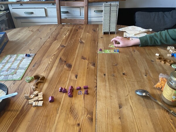 Our living room table with the first moves. In the middle we can see the tower with pieces stacked on the roof as we're playing mit more cards than its capacity.