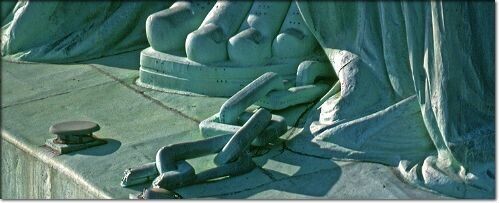 Photograph of broken chains at the feet of the statue of Liberty.