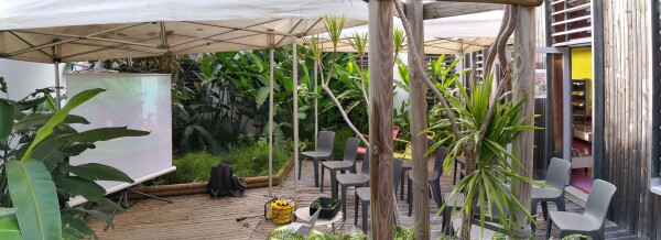 One of the room set for the talks. A screen, a projector, a computer, many empty chairs on a terrace surrounded by endemic plants and tree of the island. 