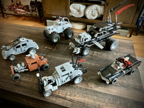 Five custom LEGO models of various Mad Max: Fury Road vehicles set on a coffee table. From left to right, front to back: The Buick, the Elvis, Nux’s car, Caltrop #5, Big Foot and the Gigahorse