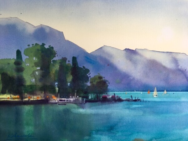 Painting of the blue lake Garda in Italy, with mountains in various shades of purple on the horizon. There are a few small boats on the lake. On the left in the lake is a strip of soil with many green trees on it. The green of the trees is refelected in the lake. The sky is light yellow just above the horizon, and light blue above.