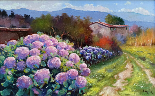 Painting of a countryside with two greyish purple houses with orange roofs in the background. In the foreground on the left is a big plant with many rather large pink and purple coloured flowers, with light green leaves. On the right is a sandy path with light green grass in it, leading to the houses. On the left of the path are more large purple flowers and a red bush. Left next to the houses are green and purple coloured trees. There is a brownish bordeaux stone wall behind these trees and the houses. Behind this wall are more trees in the colours dark green, and various shades of purple. Behind the houses you see the top of a green tree, and right next to the houses are little yellow trees and a pink tree. On the horizon are blue hills. The sky is blue with white clouds with some touches of light pink on them.