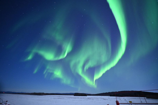 Northern Lights in bright green over the snow in North Pole, Alaska.