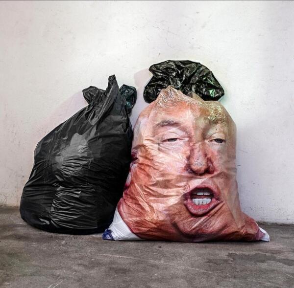 Photography and art. A photo of two garbage bags standing on the ground. One of them is plain black, the other bag is covered with a large male face made of foil. The face is Donald Trump with his mouth open. The photo is a reaction to the unspeakable insults directed at Puerto Rico and its residents by a so-called "comedian" at a Trump campaign rally, and the actions that followed.