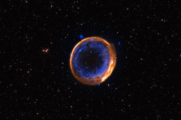 A cosmic bubble against a starry background. The outer layer of the bubble is orange, and it surrounds an inner blue layer.