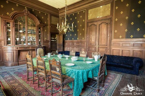 dining room with wooden panel walls, the table has a green tablecloth