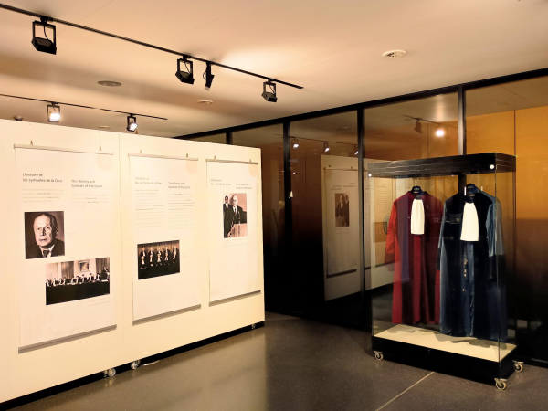 Exposition inside the Court of Justice of the European Union. It shows a panel with historical elements and two judge robes, a red and a blue one.