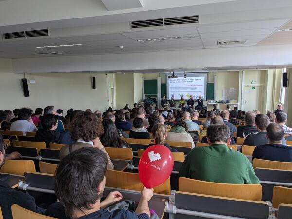 lecture hall with someone in the back holding an I love free software balloon.