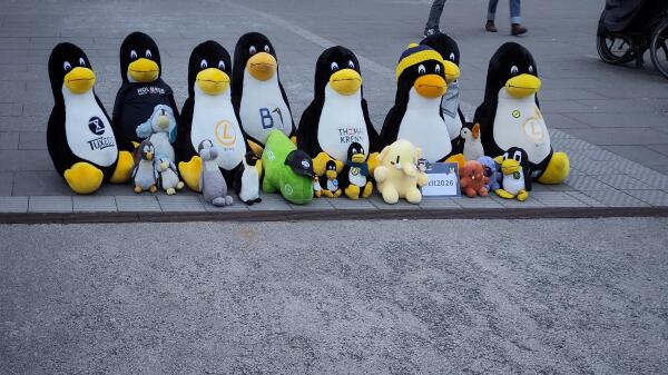 Verschiedenste Tuxe in allen Größen, Plushtodons und ein Suse Maskottchen sind als Gruppe aufgereiht