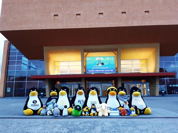 Viele große und kleine Pinguine und andere Plüschfiguren sitzen vor dem Gebäude.