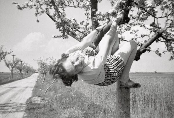 a black-and-white snapshot of a woman in a tree