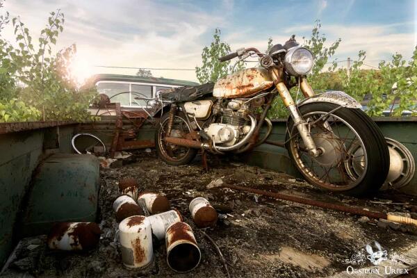 A rusted vintage motorcycle rests in the bed of an abandoned pick-up truck, surrounded by other decaying items under a bright sky.