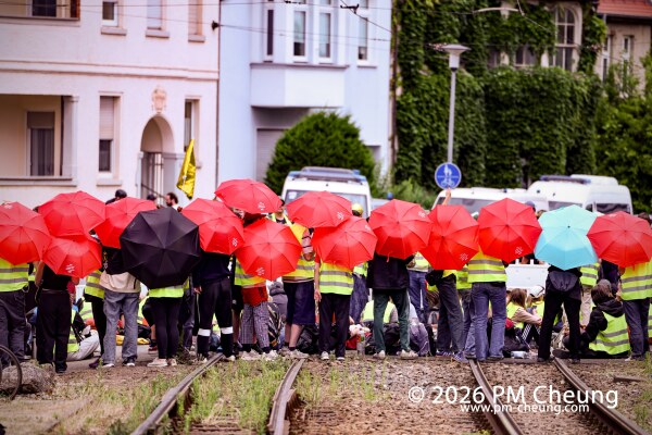 Am Gothaer Platz schützen sich Demonstrant*innen mit aufgespannten Regenschirme von rechten Streamern.