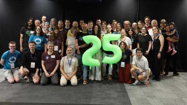 Group picture with two balloons in the shape of he numbers 2 and 5
