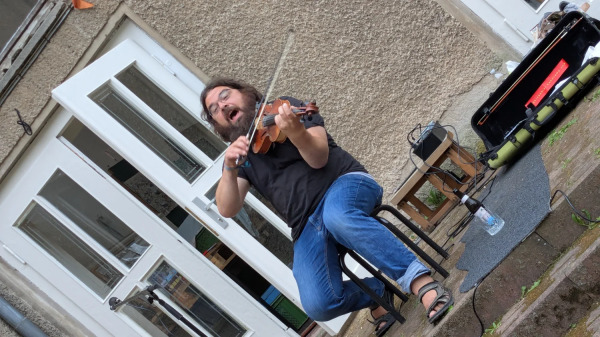Geigerzähler mit Bart, Brille und Geige live in Action draußen vorm Haus des Wandels 