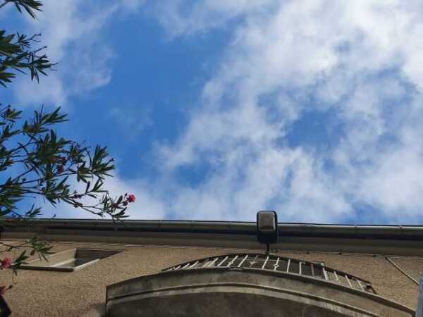 Blauer Himmel, ein paar Wölkchen, Foto aufgenommen entlang der Hausfront des Haus des Wandels