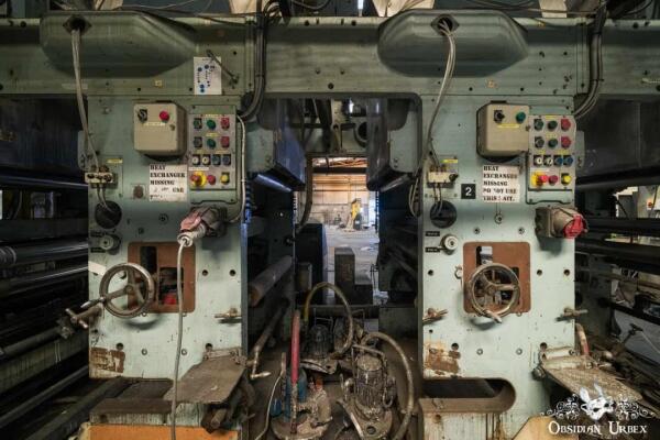 Two symmetrical industrial machines from an abandoned wallpaper factory, with control panels featuring dials and levers.