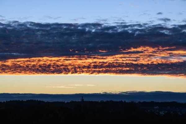Landschaft mit tiefliegenden Wolken, die beleuchtet von der Sonne sind.